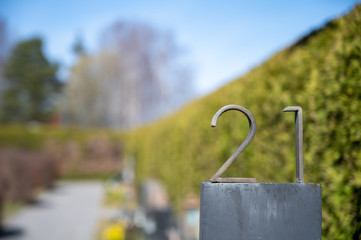 Obraz na płótnie Canvas Closeup of metal number 21 sign agains green bush background.