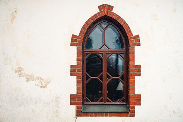 A detailed closeup of an medieval arch window with red brick frame and white background.