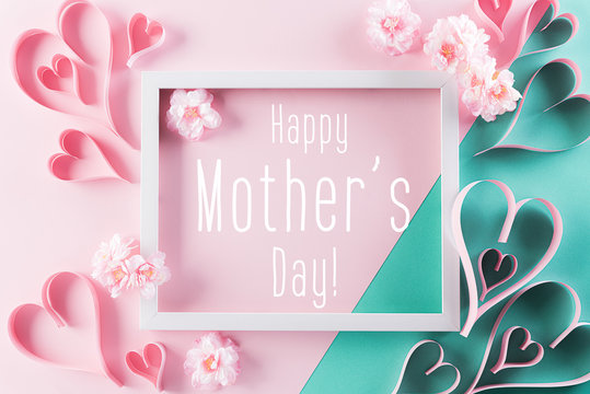 Happy Mother's Day, Women's Day or Valentine's Day greeting concept. Pastel Pink Colours Background with picture frame, handmade heart and blossom flowers flat lay patterns.