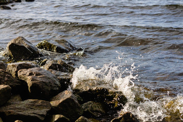 Rocky riverbank. Waves rise against rocks.