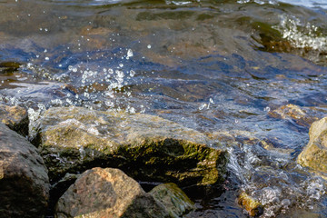 Rocky riverbank. Waves rise against rocks.