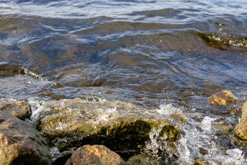 Rocky riverbank. Waves rise against rocks.