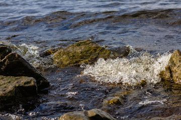 Rocky riverbank. Waves rise against rocks.