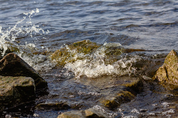 Rocky riverbank. Waves rise against rocks.