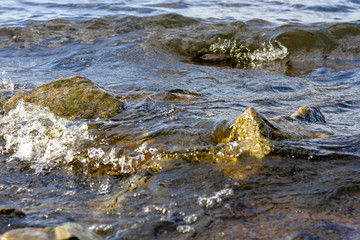 Rocky riverbank. Waves rise against rocks.