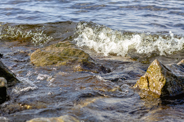 Rocky riverbank. Waves rise against rocks.