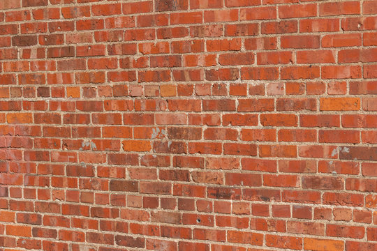 Antique exterior red clay brick wall background with severely decaying brick texture and mortar