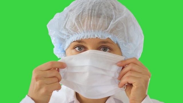 Wear the mask! Female doctor wearing a mask and pointing her finger up on a Green Screen, Chroma Key.