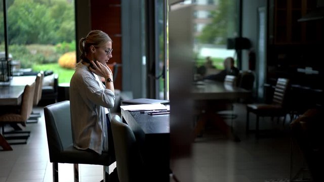 Attractive female employee doing distance job during overtime for startup project sitting at desktop with laptop and financial reports, e learning for university course work
