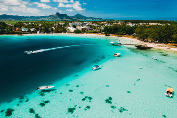 Aerial photography of the East coast of the island of Mauritius. the blue lagoon of the island of Mauritius is shot through from above. The boat is floating on a turquoise lagoon