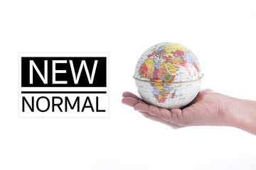 NEW NORMAL text on Globe in hand isolated on white background