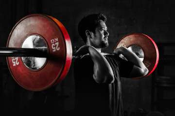 asian athletic strong man having workout and bodybuilding with barbells weightlifting front squat style in gym and fitness center in dark tone two tone