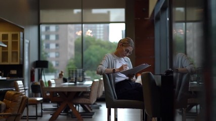 Slow motion effect of smart female student in claccis eyewear for provide eyes protection checking school project and making notes for editing printed mistakes, concept of knowledge and education
