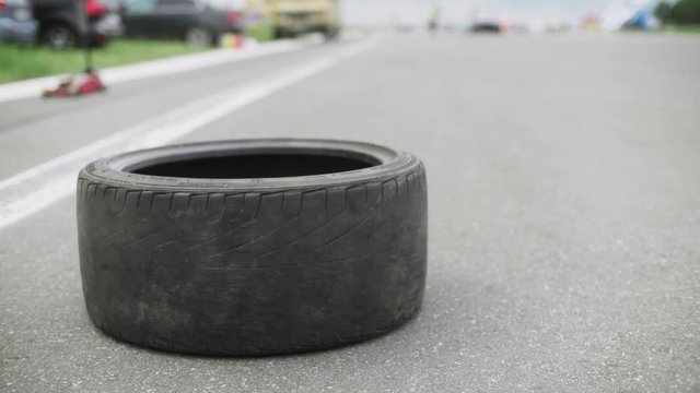Torn tire lying on a side of road. Screw jack on background. Police car pulls up