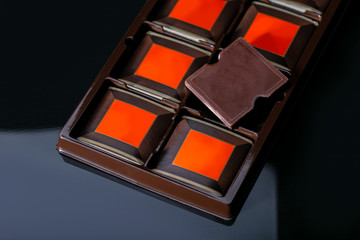 Chocolate bar in container on black background. Premium chocolate ads.