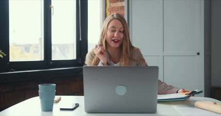 Self isolation lifestyle. Beautiful young blonde business woman works from home on laptop video call in pajamas pants.