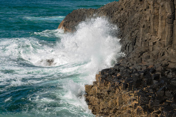 The Pacific ocean crashes into the columnar basalt rocks of Fingal Head, New South Wales