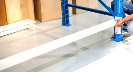 Male hand preparing to assembling the metal rack  in in warehouse or storage and shelves for cardboard boxes of products.