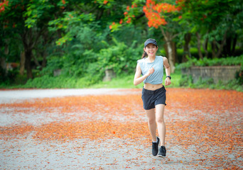 Portrait of young happiness runner woman running in the park. Running is a great way to help improve cardiovascular health,  burns calories and can build strength.