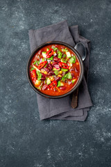 Mexican black bean tomato soup in clay bowl. Gray background