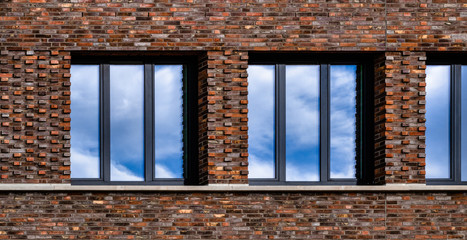 Wolkenspiegelung im Fenster eines Backsteingebäudes
