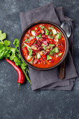 Mexican black bean tomato soup in clay bowl. Gray background