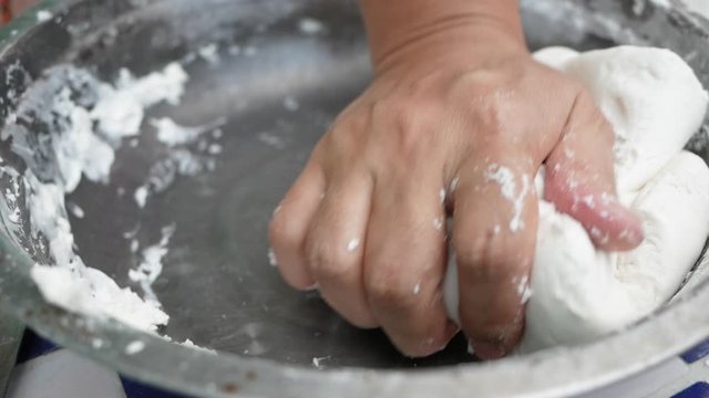 Asian young woman is making Thai dumplings dessert or Bualoy sweets. Close-up of the process of mixing flour with coconut milk and kneading the dough to make Bualoy balls.