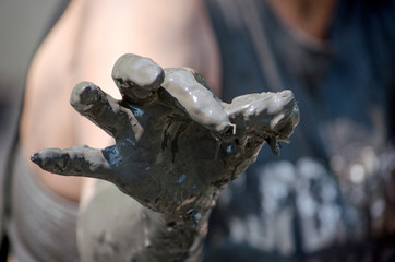 A muddy hand holds a tiny  rescued  muddy frog