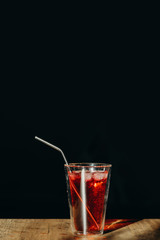 A glass of red sweet drink with metal straw or stainless straw  on wooden table.