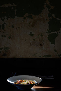 poached eggs on boudin and gravy on table in front of textured rustic wall