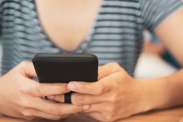 Womanhand using smartphone to do work business, social network, communication in public cafe work space.
