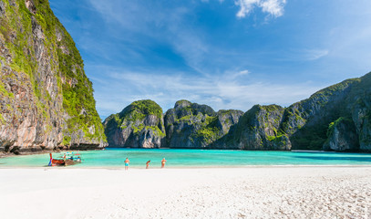 Beautiful tropical beach with white sand and turquoise ocean against blue sky with clouds on sunny summer day at Phi Phi island. Travel vacation background for relaxing vacation island of Thailand.
