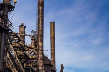 Vast steel mill complex now derelict, smoke stacks and furnaces, blue sky copy space, horizontal aspect © Natalie Schorr