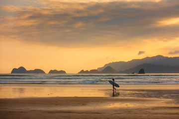 Surfer on the ocean beach at sunset