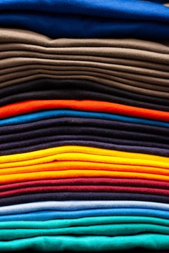 details of clothing and textile on display in clothing store folded, stacked and hanging