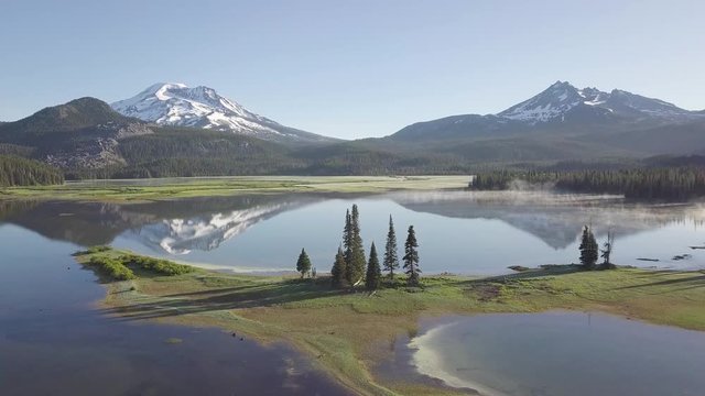 Aerial view of sunrise at Sparks Lake, Bend, Oregon, USA
Drone panorama view of picturesque northwest natural landscape with beautiful snow capped mountains in distance past tranquil lake. Volcano