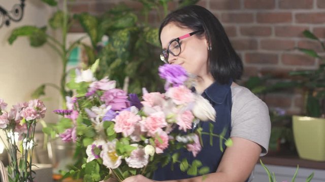 Florist woman made a bouquet of beautiful flowers. Floral art concept. Working girl in store. Professional florist making flowers bunch bouquet in flower shop. Businesswoman small business owner.