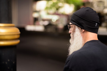 Closeup rear view of mature bearded man thinking in the city
