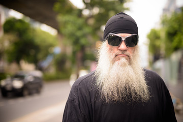 Face of mature bearded man with sunglasses in the city streets outdoors