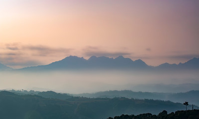 Mountain range with visible silhouettes through the morning colorful fog.