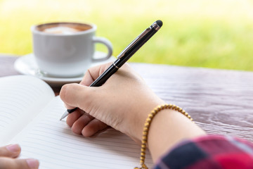 hand of women writing on note book with cup of coffee