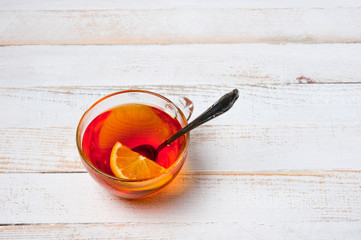 Glass cup with tea and lemon standing on a white painted wooden surface. Background for hot drinks....