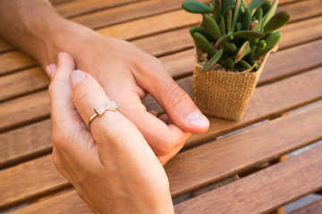 closeup of lovely couple hands holding togeher  with a plant on the wooden table,love concept, lovers having a date in a cafe