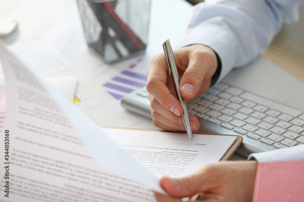 Wall mural Hand of businessman in suit filling and signing with silver pen partnership agreement form clipped to pad closeup. Management training course some important document team leader ambition concept