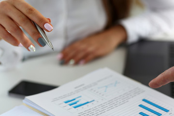 Fototapeta premium Female arm holding silver pen point in financial graph solving and discussing problem with colleague closeup. Situation examination at board council sale adviser job stock exchange market profit