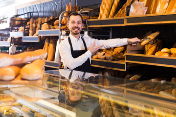 Male shop assistant demonstrating delicious loaves of bread in bakery