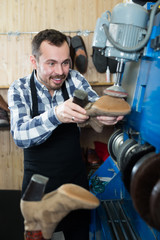 Man worker repairing shoes in repair workshop