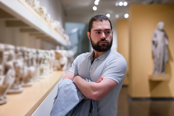 Man looking at stone architectural elements in historical museum hall