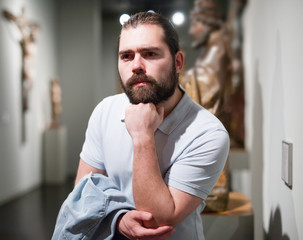 Man visiting sculpture hall in historical museum and looking at exhibits
