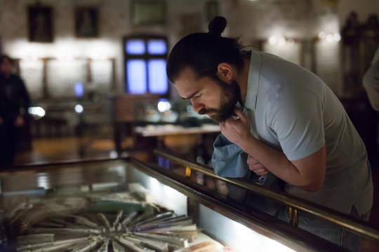 Attentive Adult Man Exploring Artworks In Glass Case In Museum